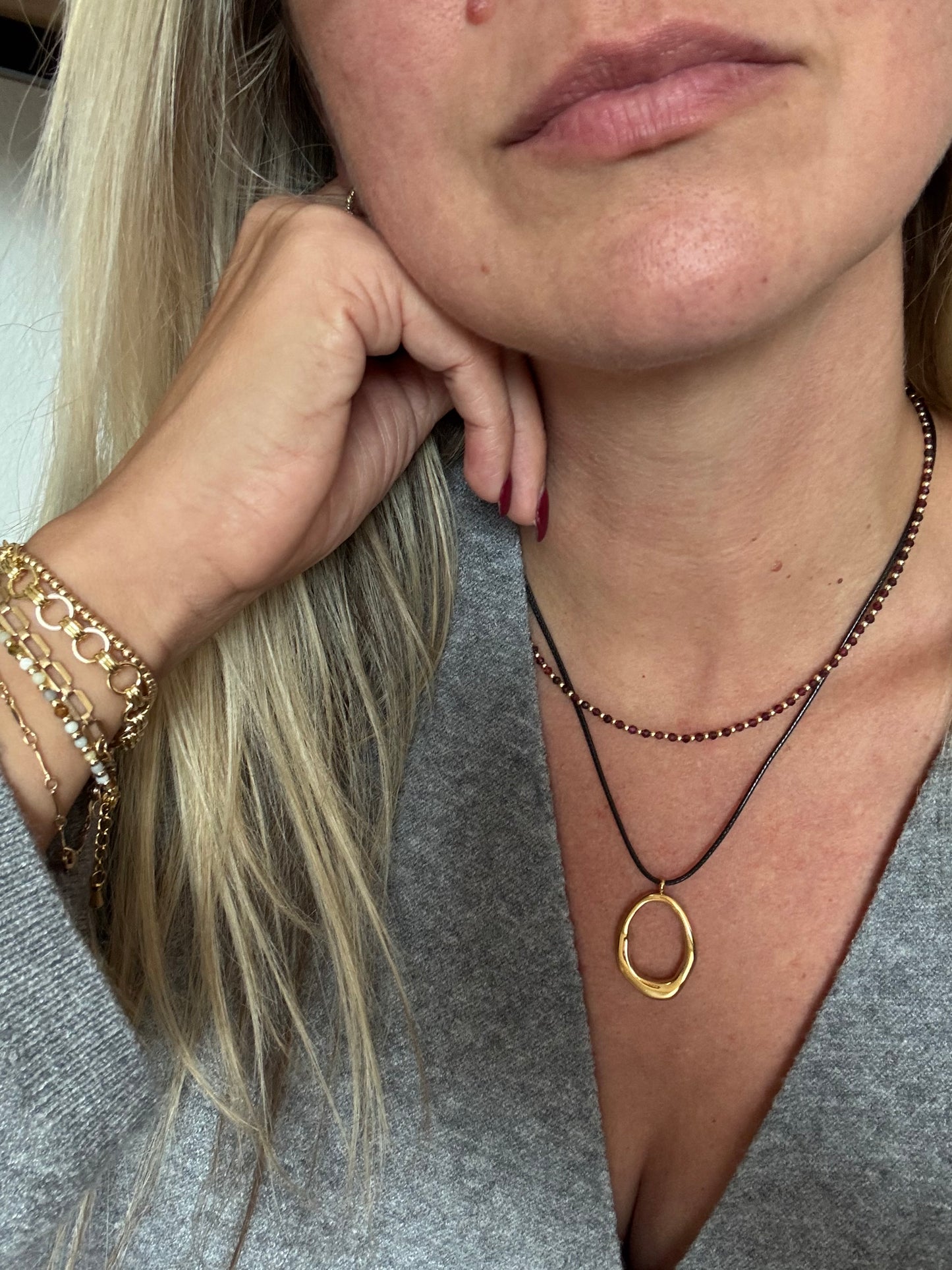 Close up of the Autum necklace on model. Featuring black cord and gold oblong pendant