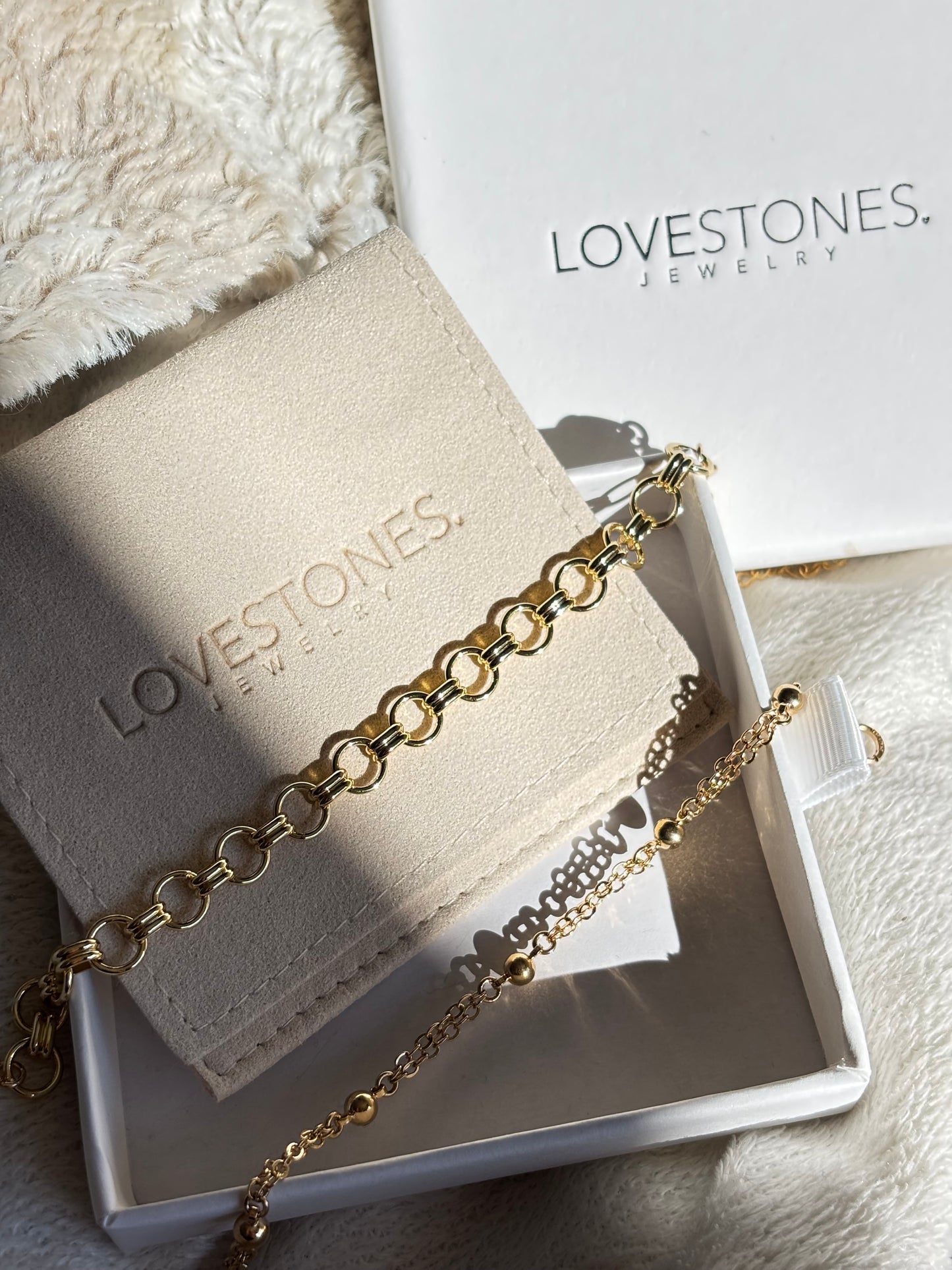 Gold overlay bracelets on a Lovestones jewelry box with a soft white background