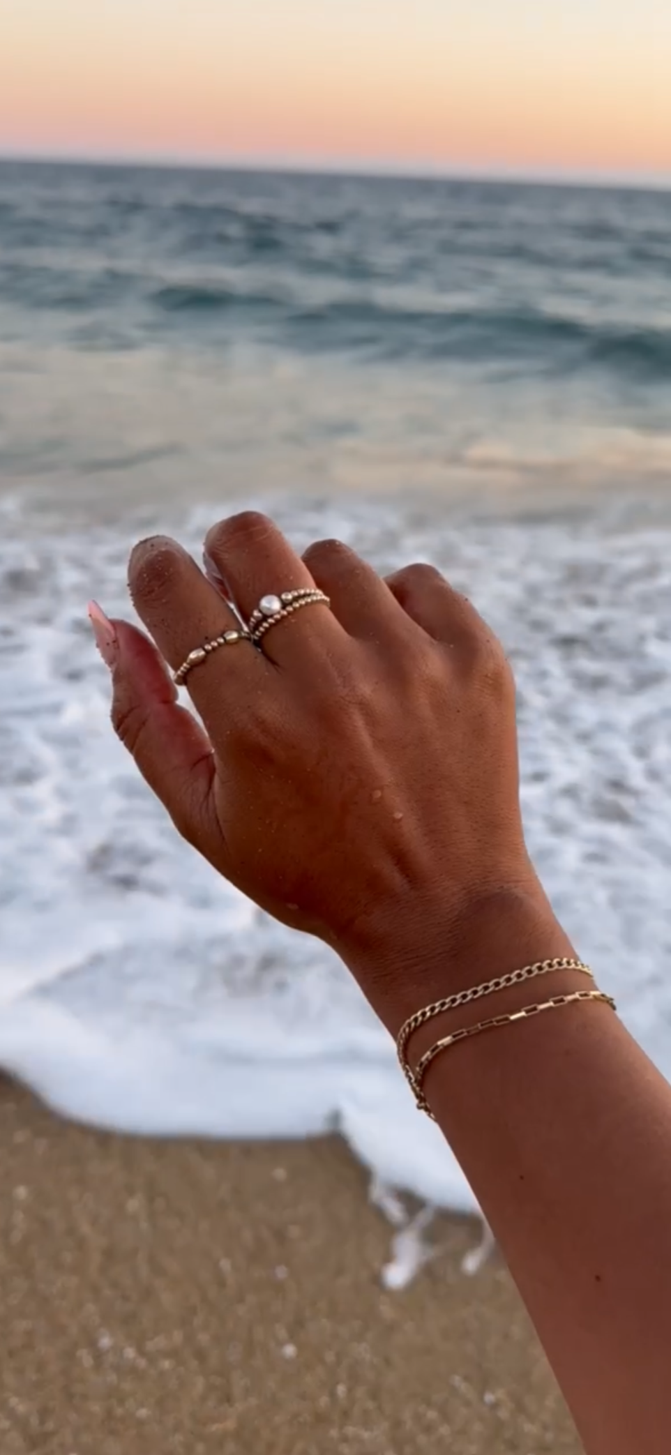 pearl and gold filled beaded ring on hand with ocean