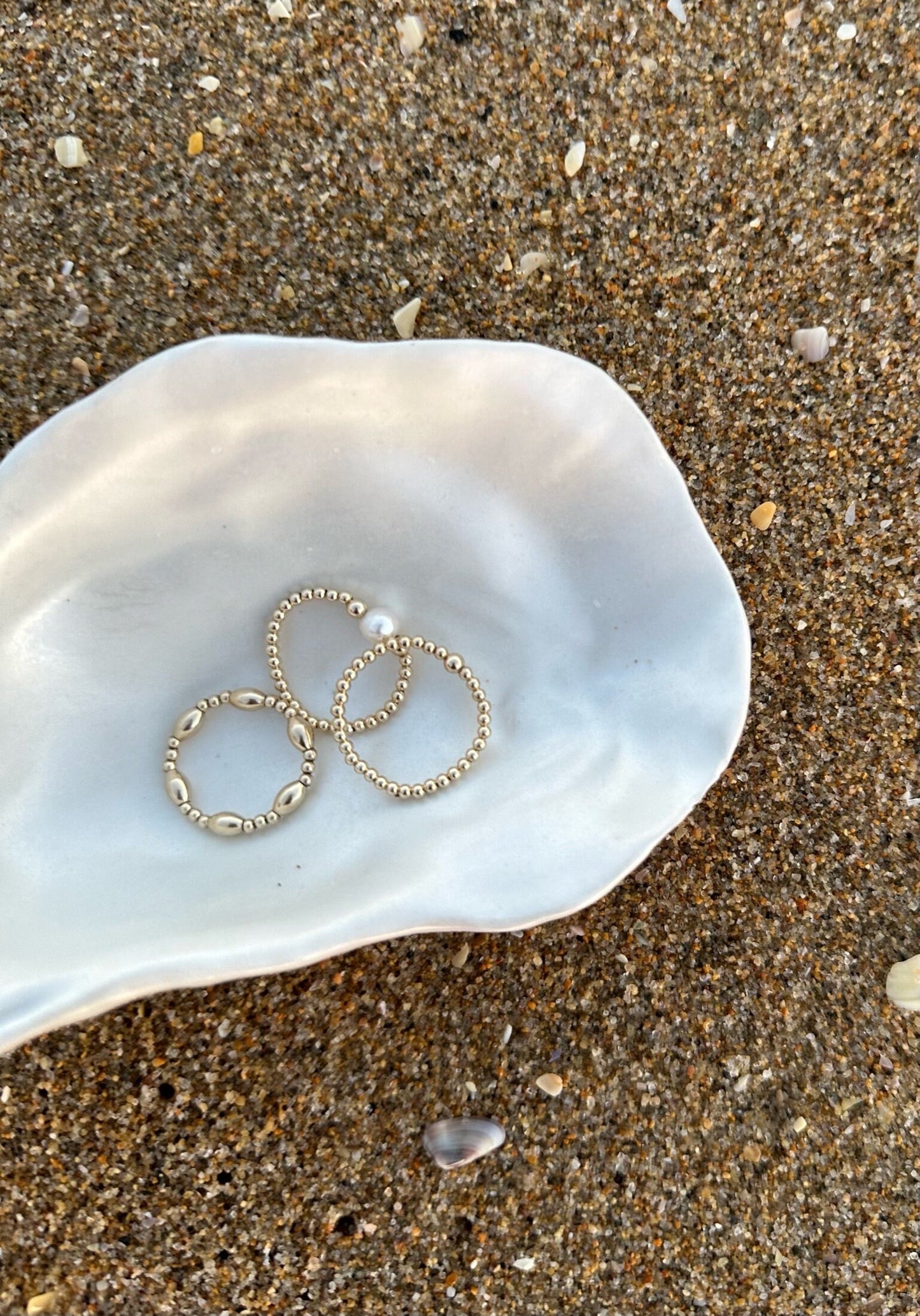 Three gold filled ring styles in shell on sand