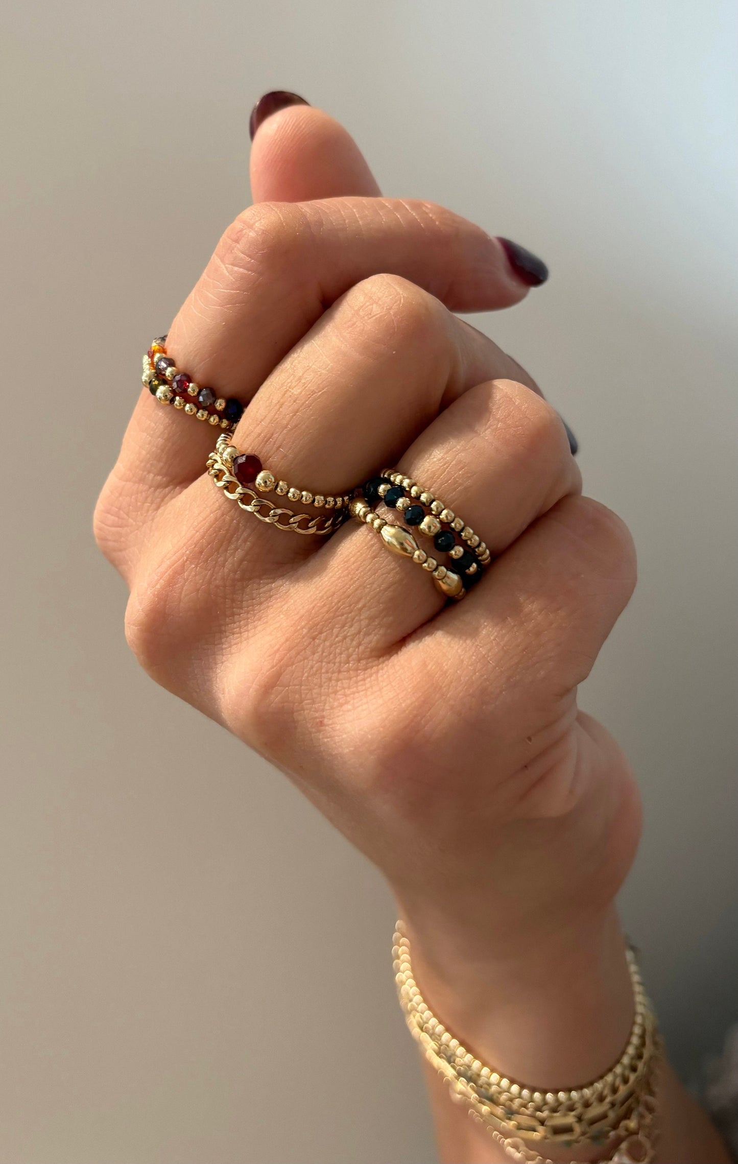 multi colored gem ring with gold beads on hand
