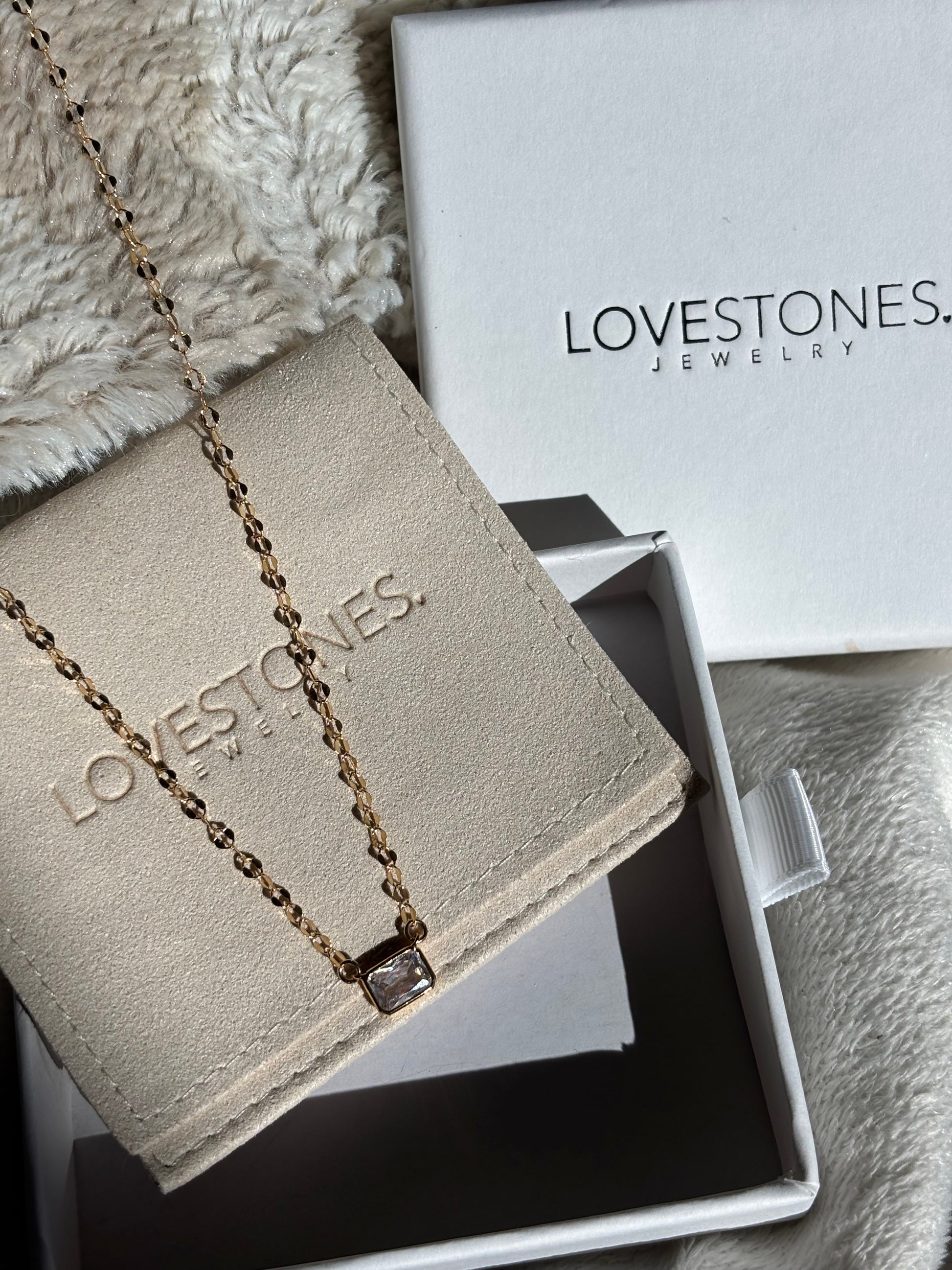 Necklace on a branded jewelry box with 'LOVESTONES' packaging in the background.