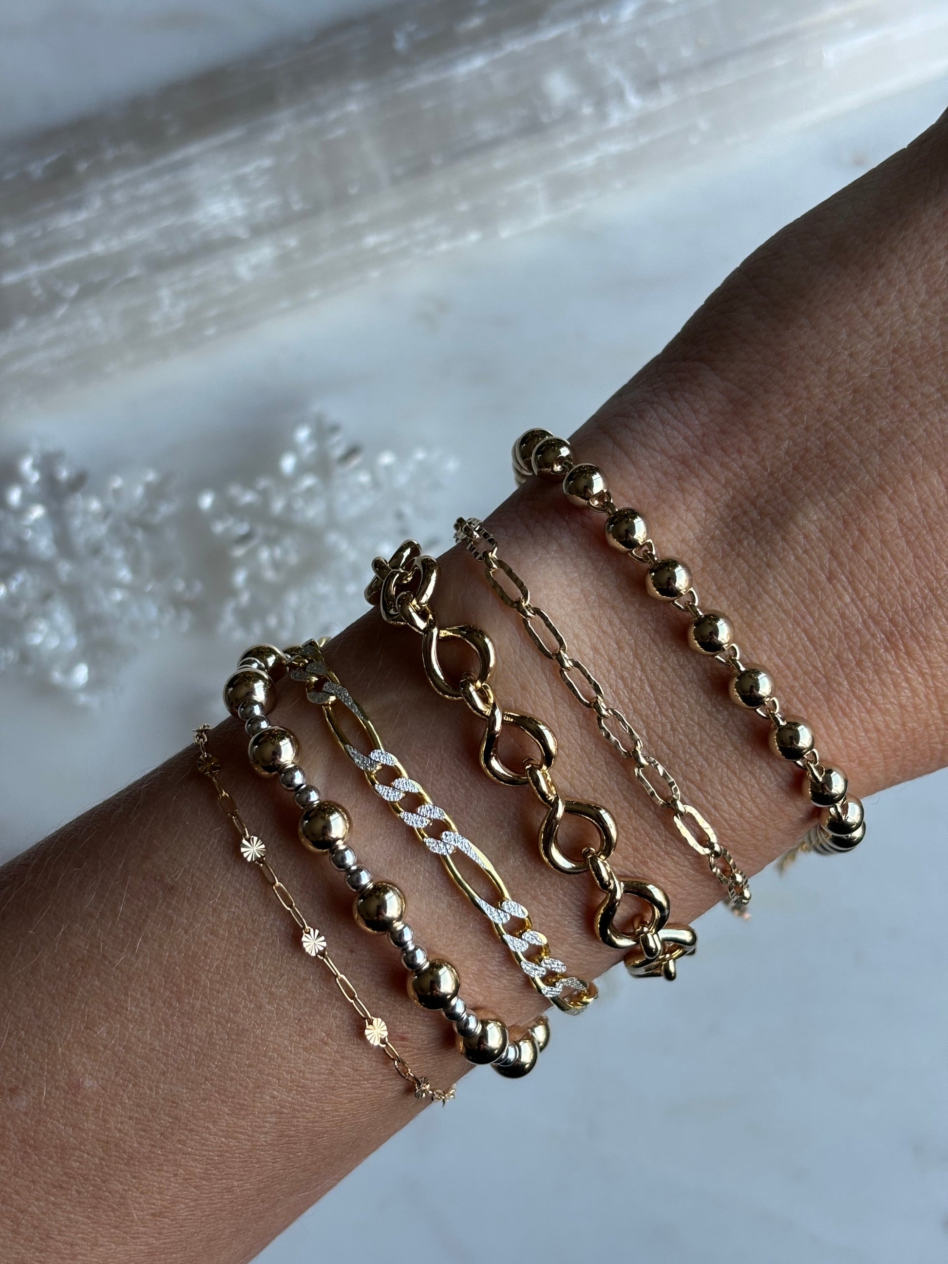 photo of 6 bracelets on model wrist on a white background with snowflake