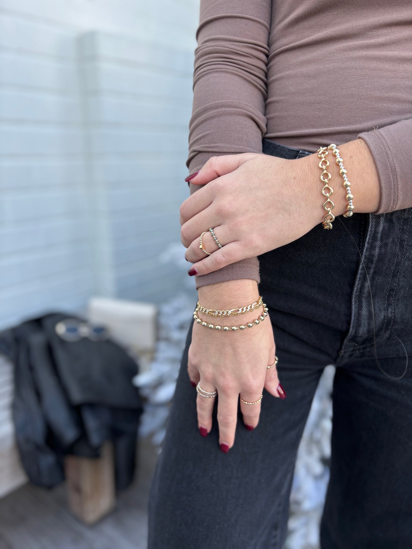 Model wearing a selection of gold and silver bracelets and rings in front of a christmas tree