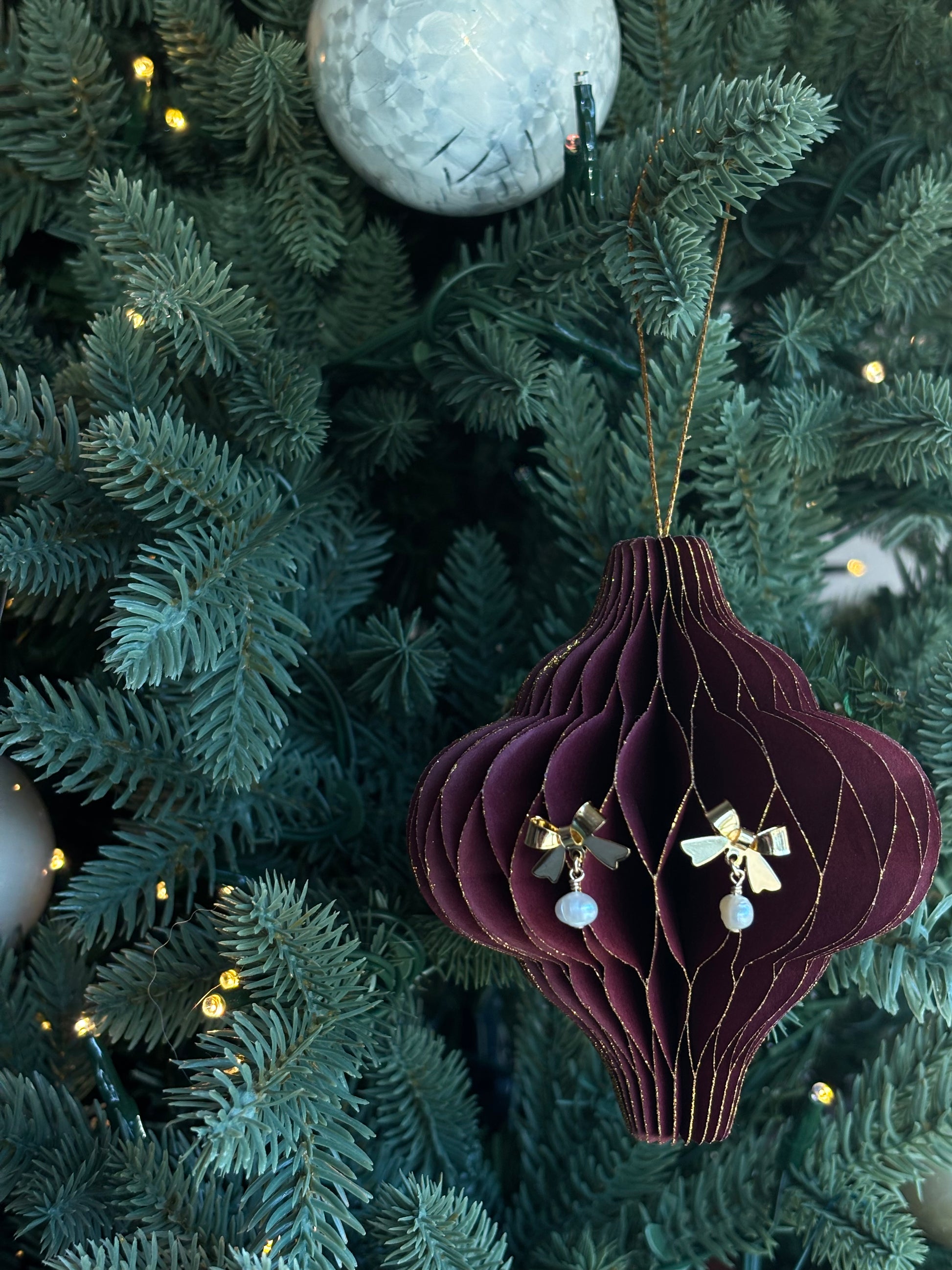 bow and pearl earrings hanging as on ornament on a tree